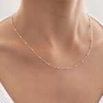 Sidabrinė grandinėlė su mažais burbuliukais ant moters kaklo